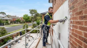 Professional tradesman applying acrylic render to the exterior wall of a Melbourne home to improve property value and weather protection.